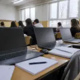 O sală de clasă cu elevi văzuți de la spate, așezați în bănci