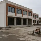 O clădire modernă de școală sau campus școlar cu două etaje, aflată în faza finală de construcție sau recent finalizată