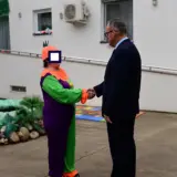 Man in suit shaking hands with a person in a colorful costume at a care center