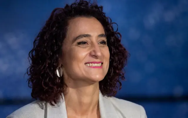 Portrait of the Romanian Minister of Culture, Raluca Turcan, smiling against a blurred blue background